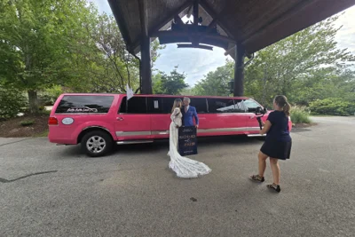Bride and groom posing in front of Pinkey the pink wedding limo in Springfield MO