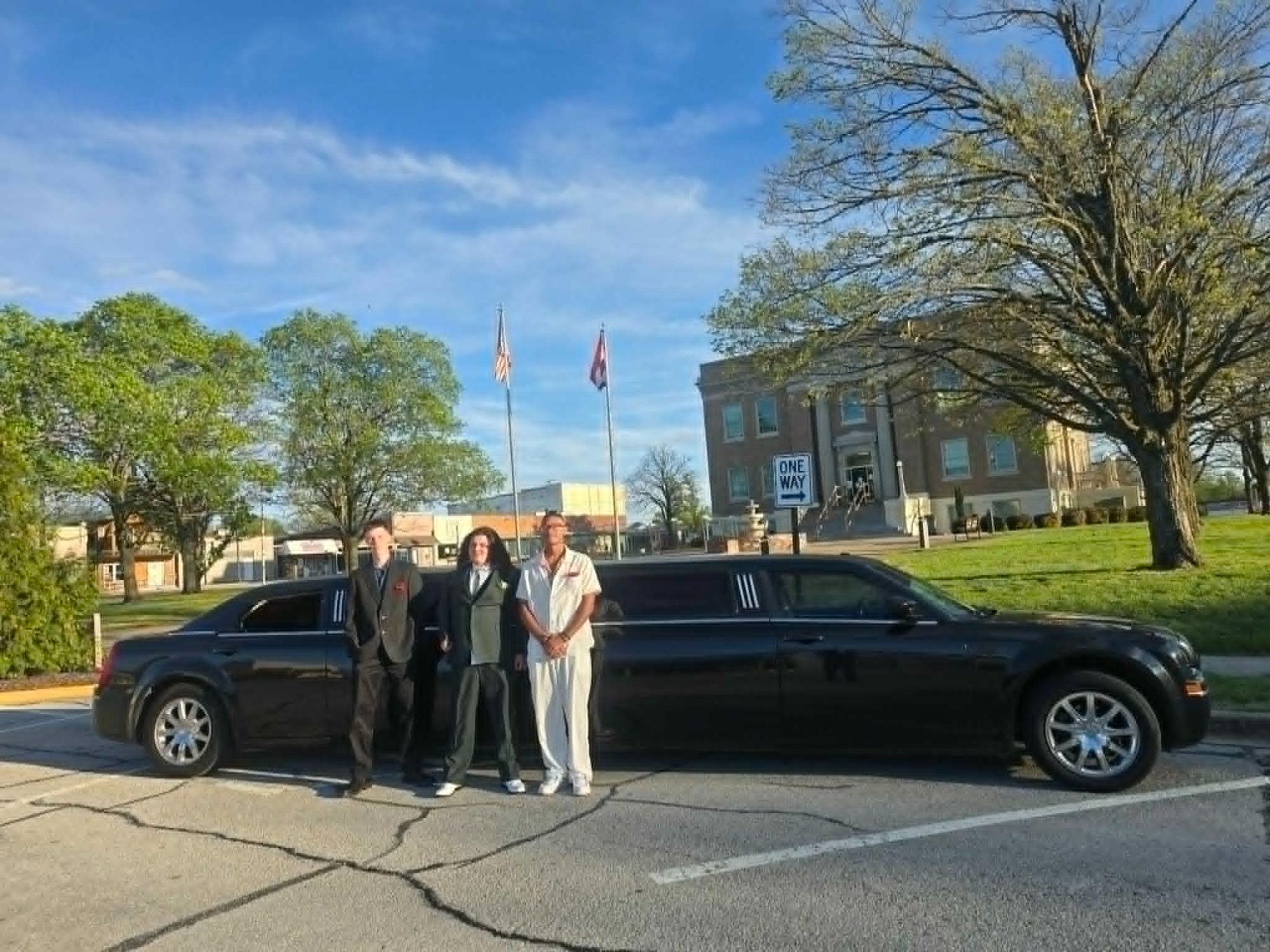 Mom, son in a suit, and Kevin the chauffeur posing in front of The Executive stretch limo downtown Springfield MO near the courthouse — Unique Rides Transportation parent prom experience
