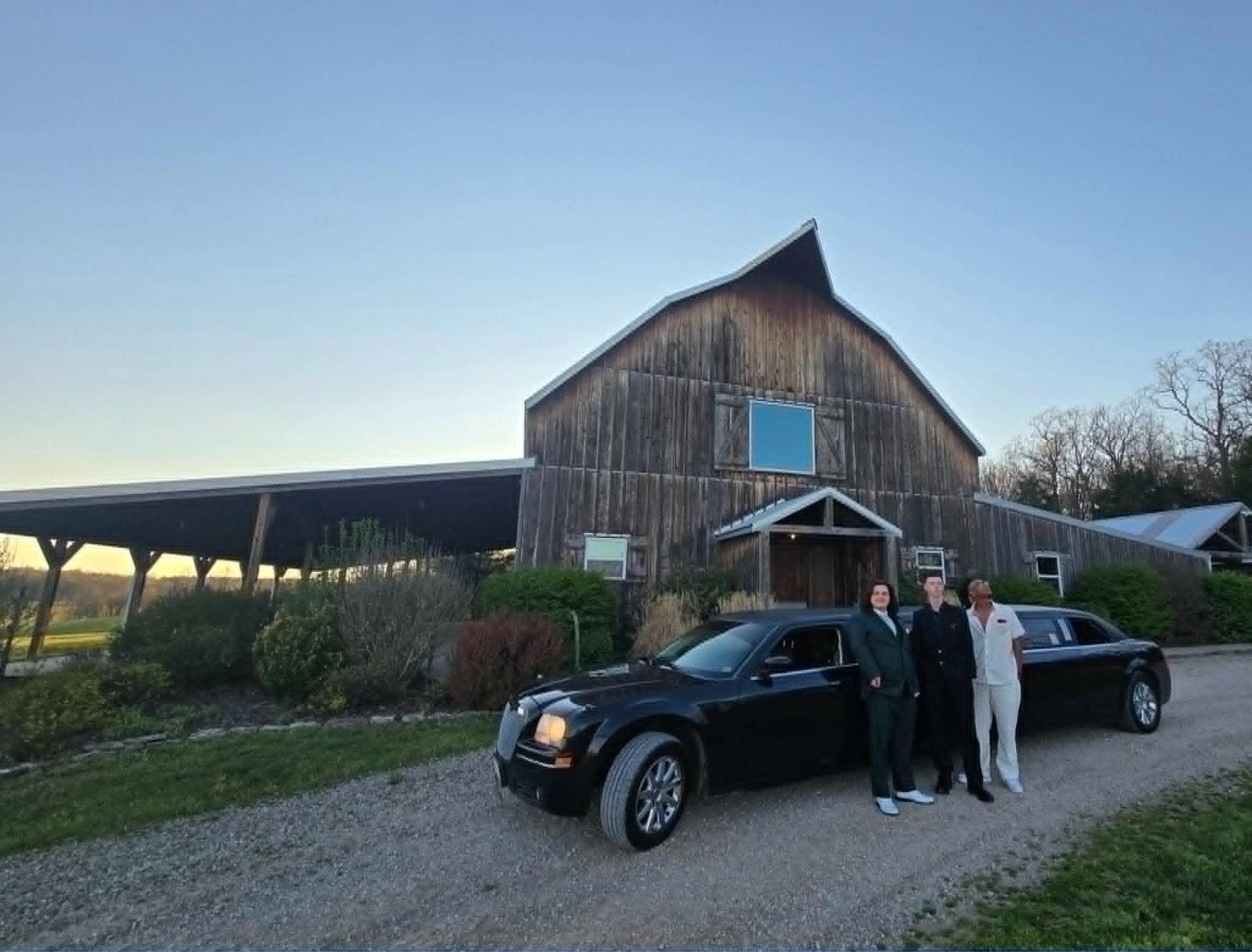 Family with their son standing in front of The Executive stretch limo at a rustic Ozarks barn at golden hour — Unique Rides Transportation Springfield MO